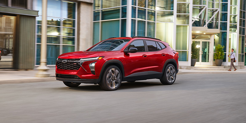 Red Chevrolet Trax SUV driving through a city street.
