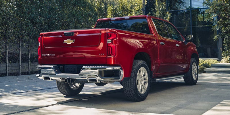 Red Chevrolet Silverado 1500 pickup truck rear view on city street