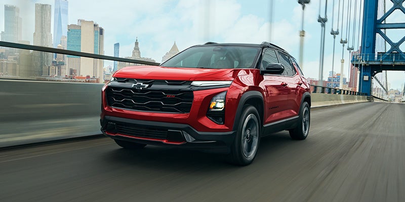 Red Chevrolet Equinox SUV driving on a city bridge with modern styling.